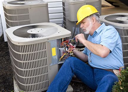 A Man in a Hard Hat Is Repairing an Hvac Unit, Focused On His Work in a Mechanical Setting.