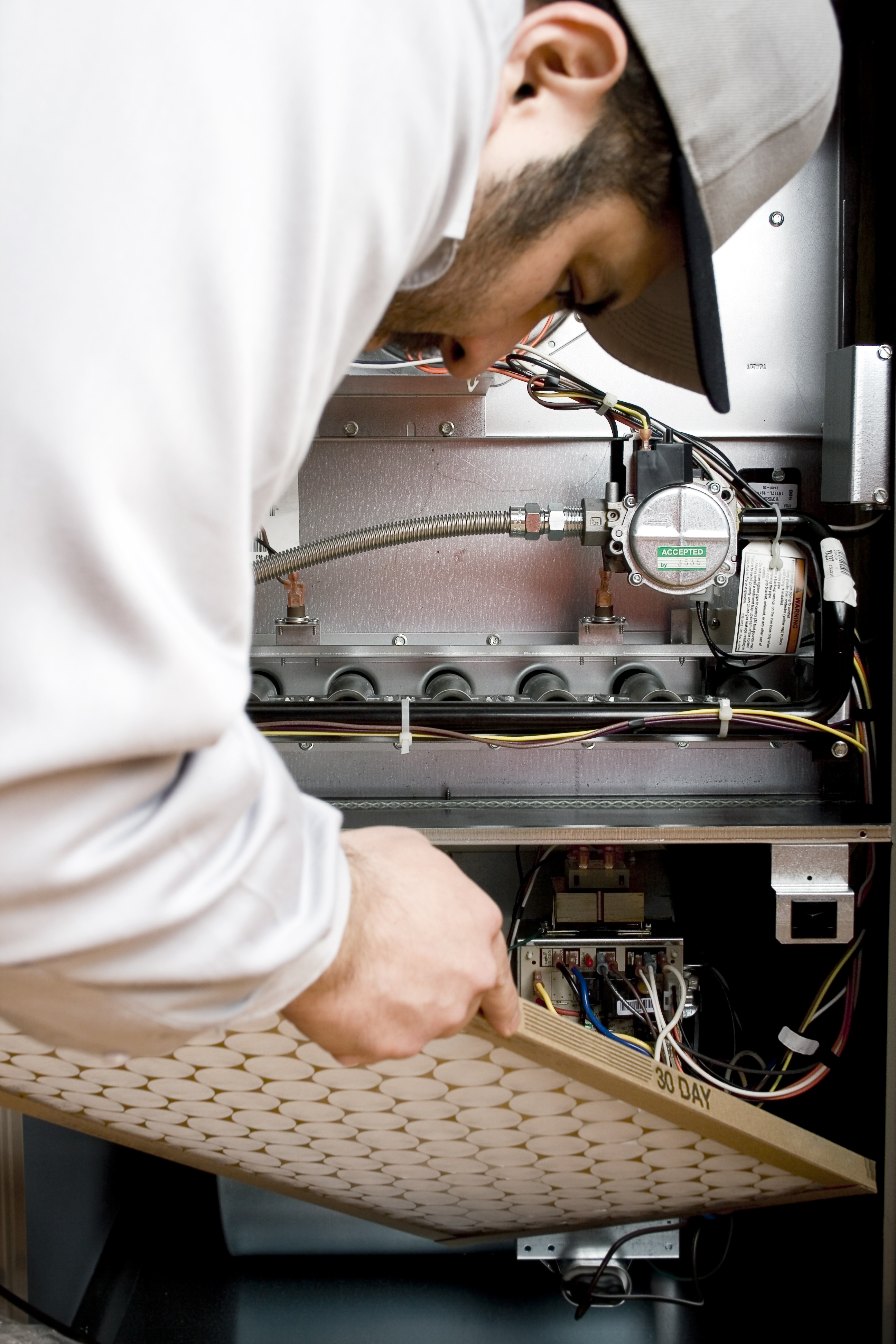 A man repairs a furnace in a cozy home, focused on fixing the heating system for comfort.